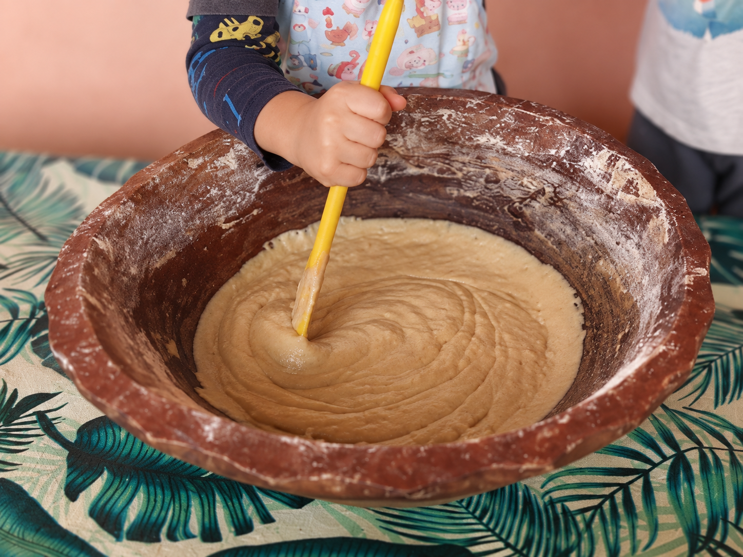 Mão de uma criança misturando ingredientes em uma tigela
